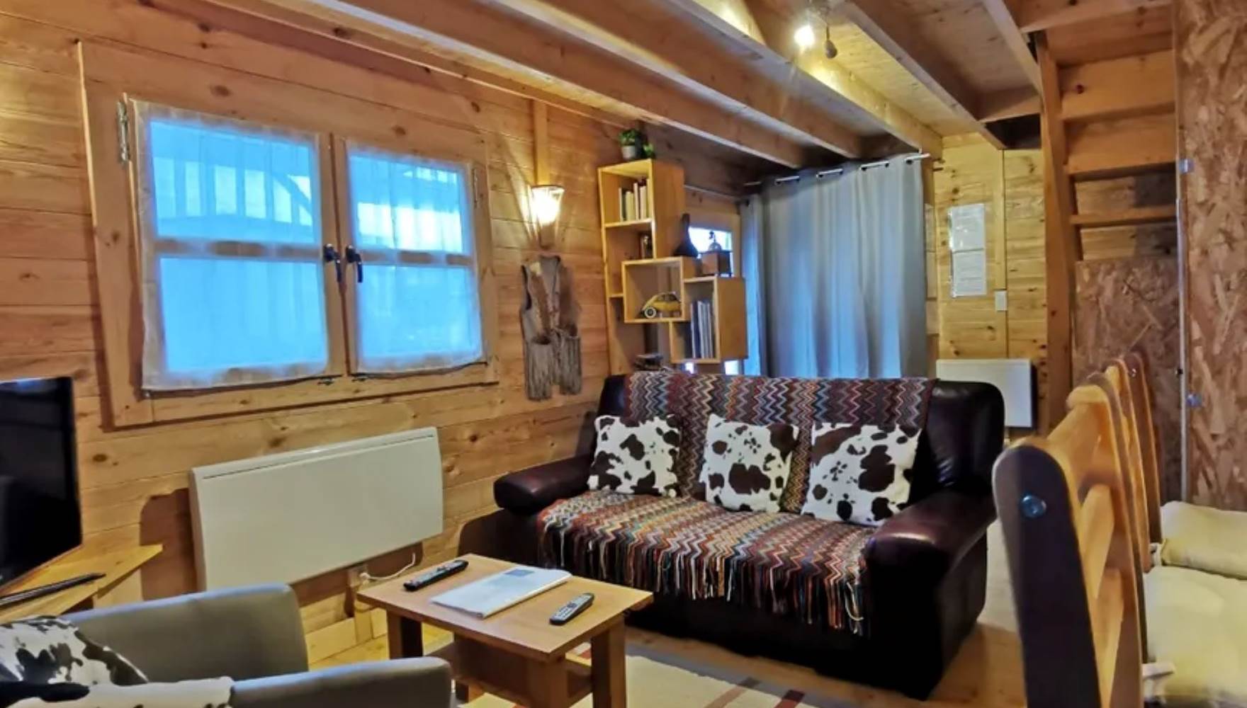 Salon chaleureux en bois avec télévision et bibliothèque, parfait pour un séjour cosy aux Chalets de Kerescar à Plouarzel