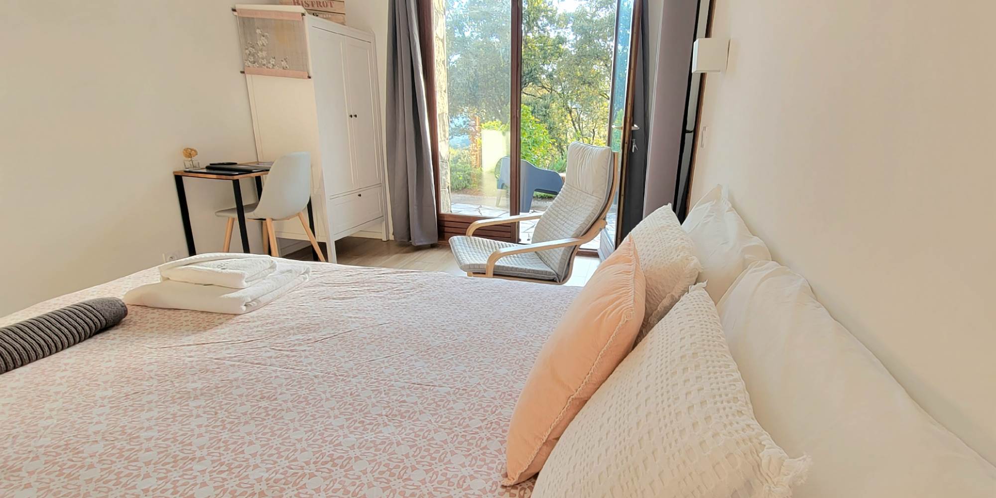 Intérieur d'une chambre d'hôtes décorée avec goût offrant une vue dégagée sur le jardin.