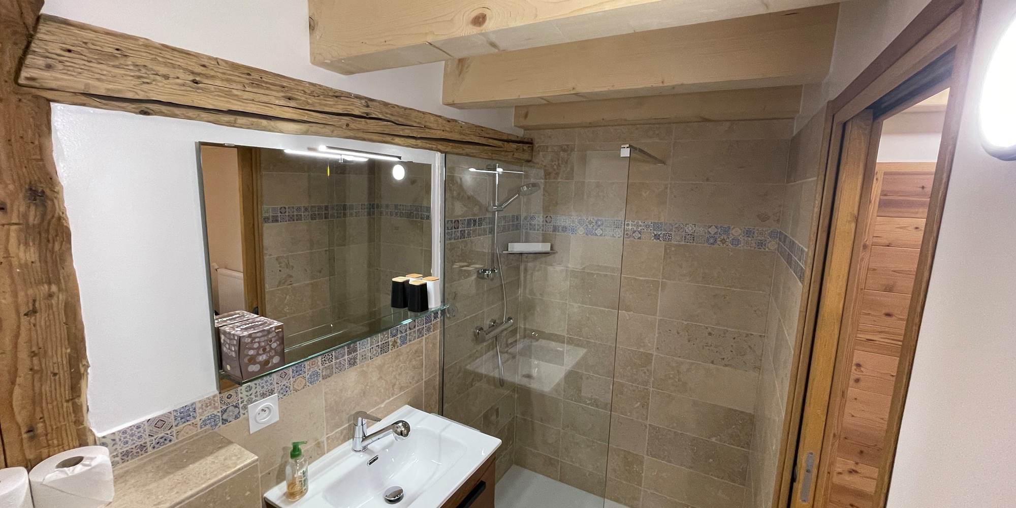 Salle de bain avec lavabo, douche, WC, sèche serviette et sèche cheveux.