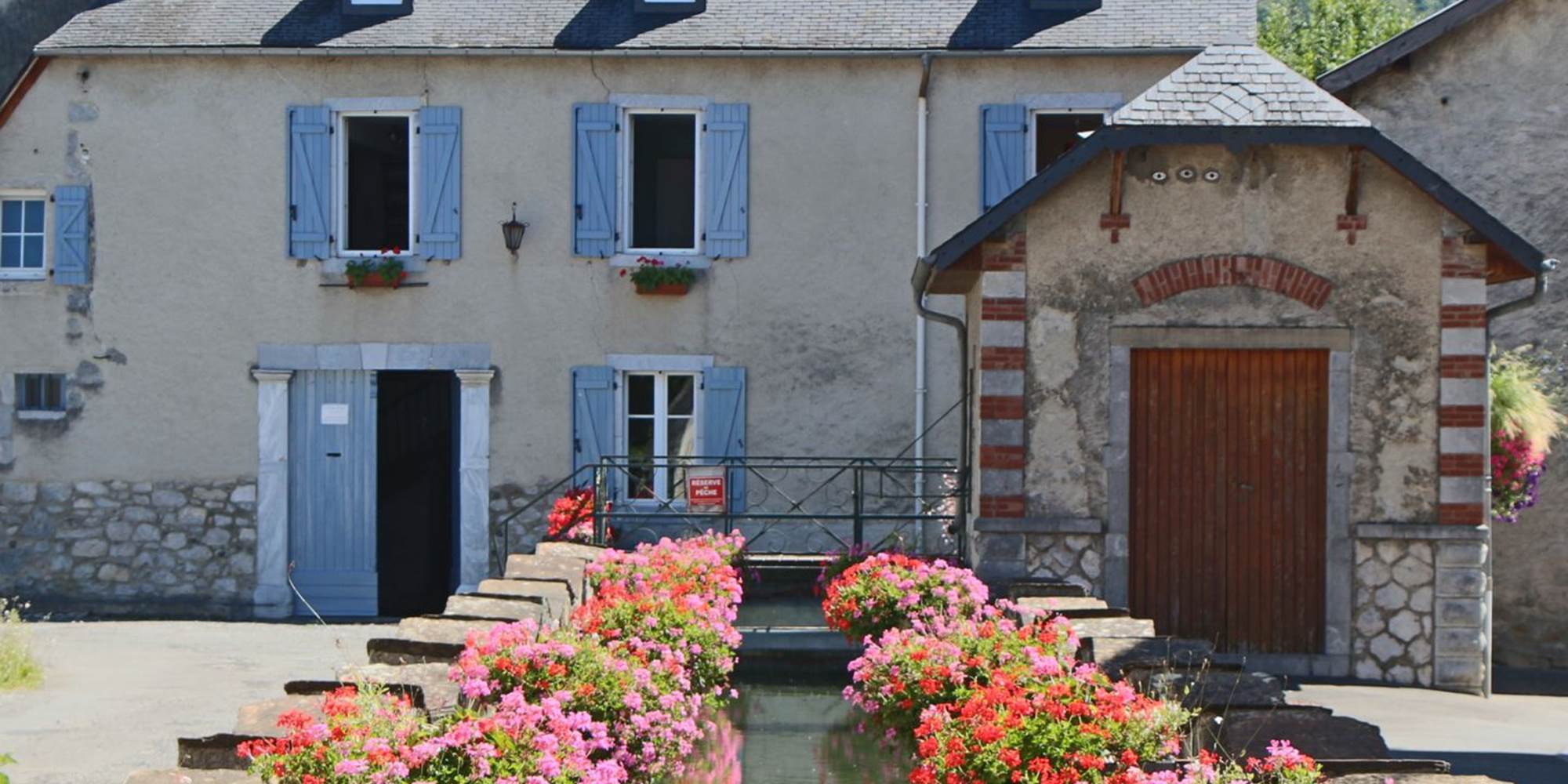 Gîte du Moulin : Le canal fleuri et la façade du moulin.