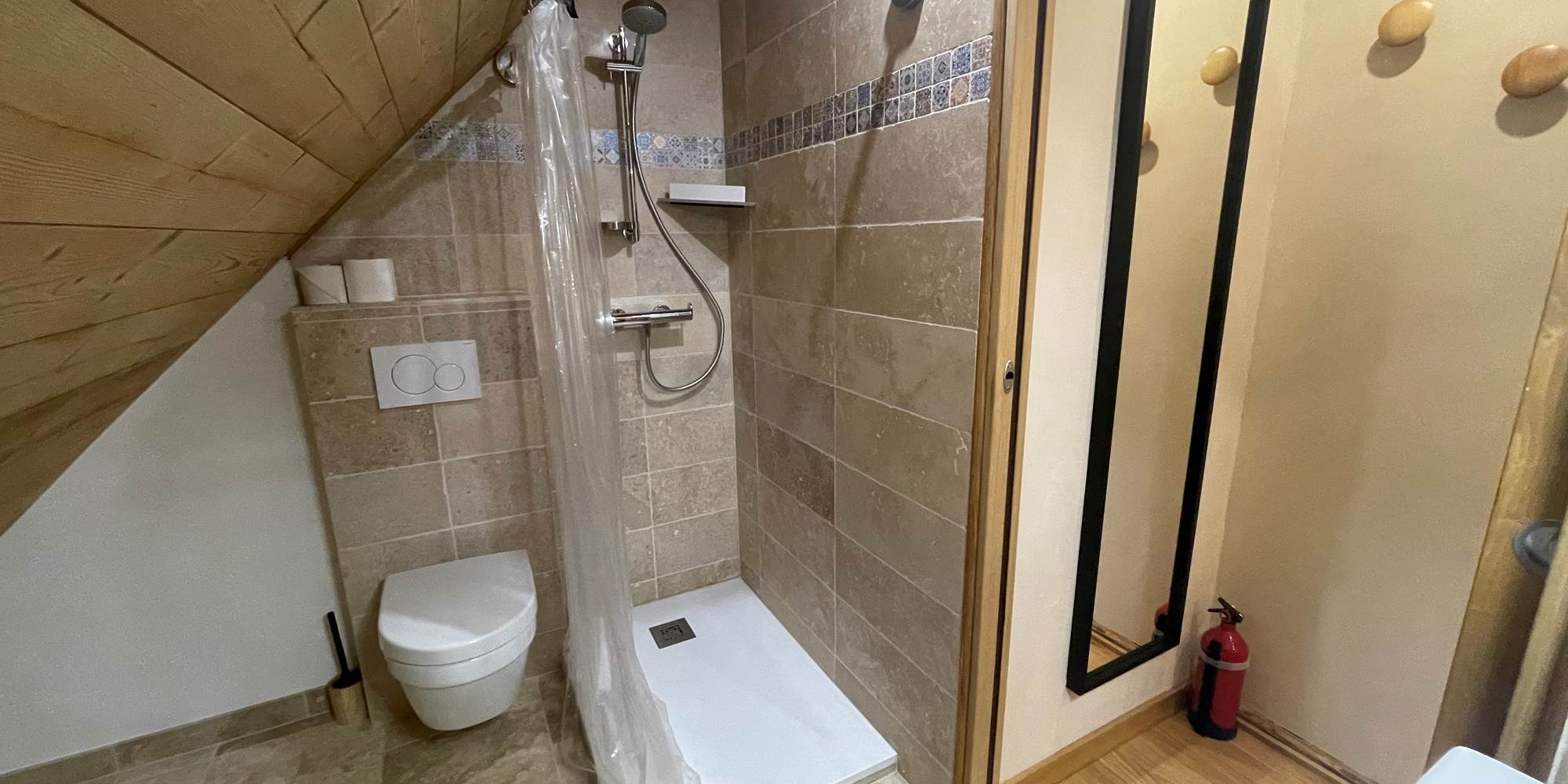 Salle de bain avec douche chaude et WC.