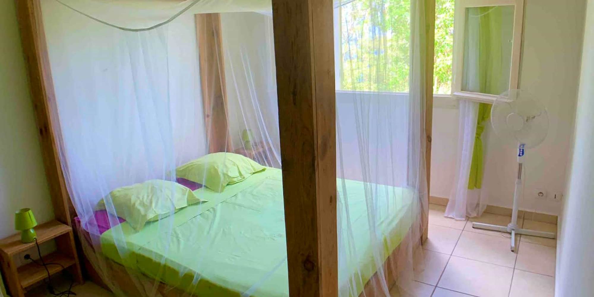 Chambre ventilée avec lit à baldaquin et moustiquaire