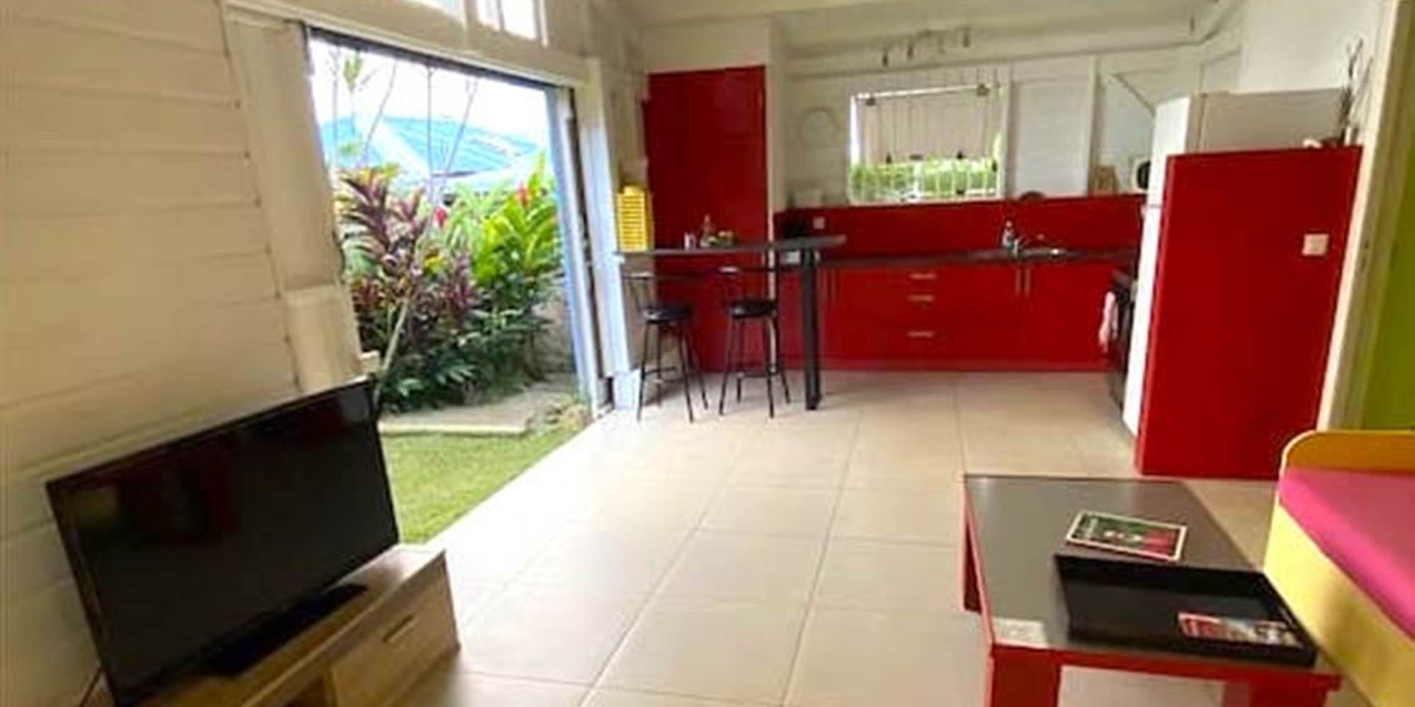 Séjour vers la cuisine avec grande ouverture sur le jardin