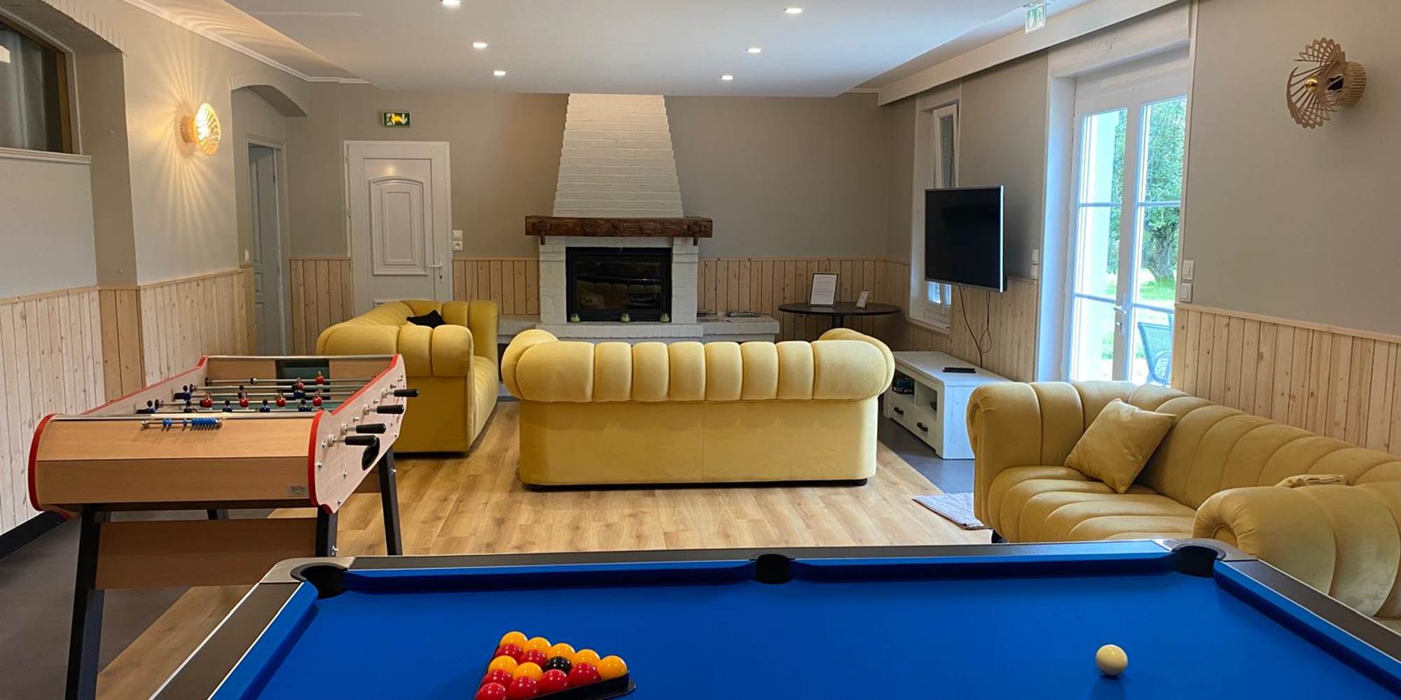 Espace détente lumineux avec cheminée, jeux et TV : tout le confort d’un gîte rural de charme en Hauts-de-France