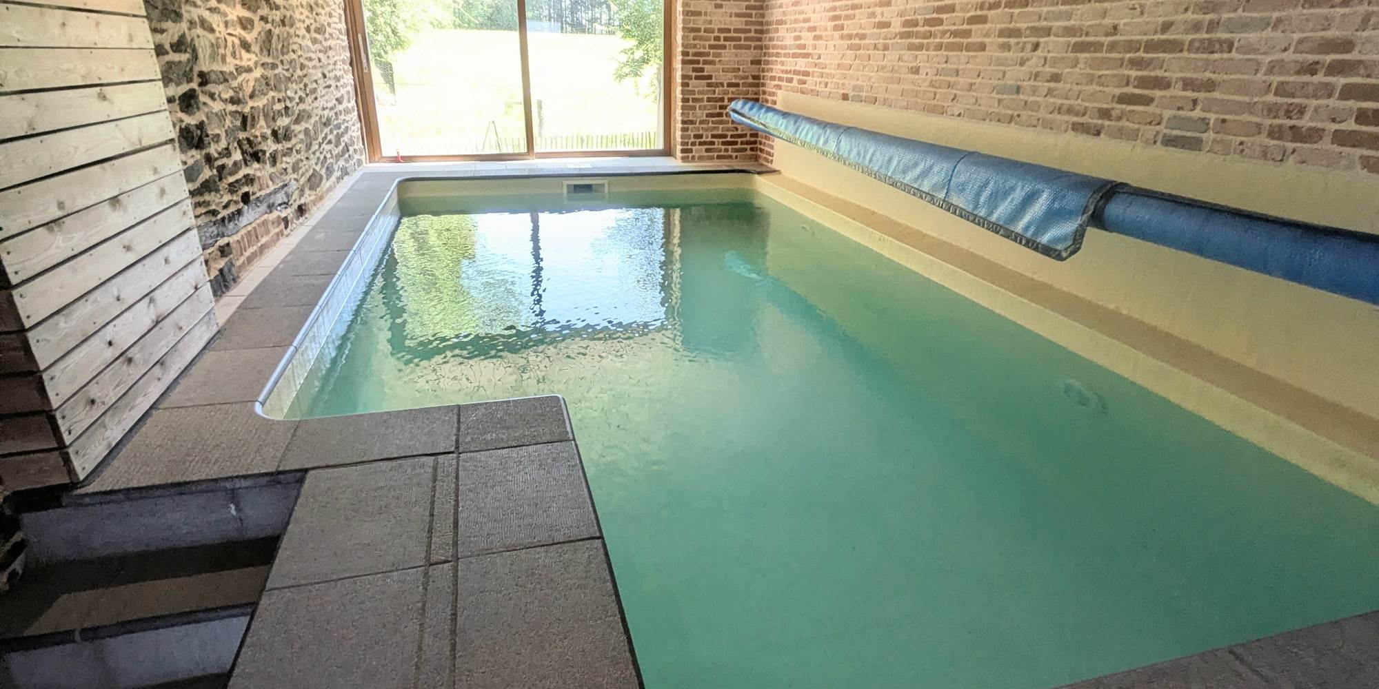 alt="Espace piscine couverte avec ambiance détente dans le gîte familial avec piscine en Belgique"