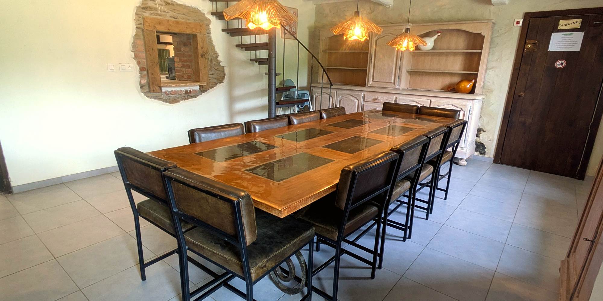 Bright family dining room with large table and children’s seating in holiday gîte