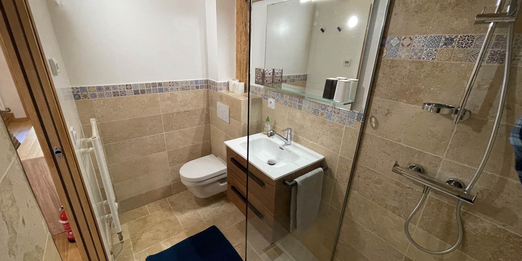 Salle de bain avec lavabo, douche, WC, sèche serviette et sèche cheveux.