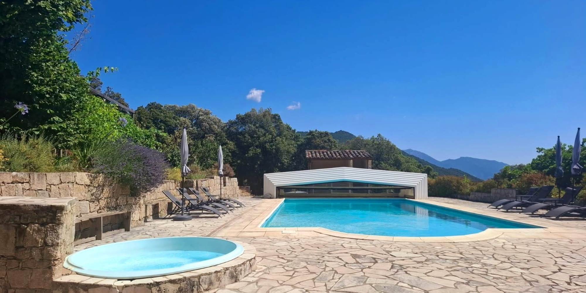 Grande piscine extérieure et jacuzzi avec vue panoramique sur les montagnes corses.
