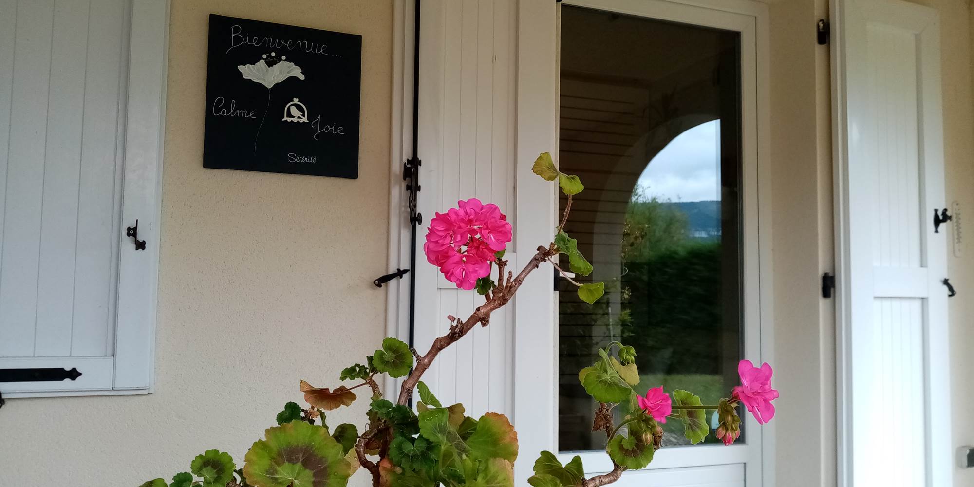 Fleur sous la terrasse couverte et entrée dans le Gîte