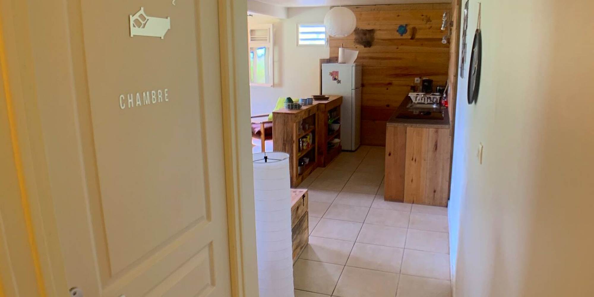 Vue du couloir vers le séjour avec porte de la chambre