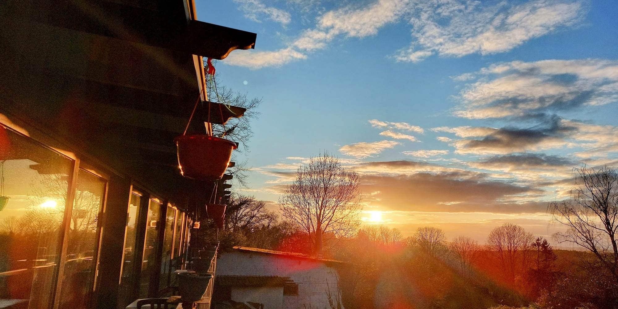 Le soleil couchant joue à -ric hochet- sur les baies vitrées de la salle à manger panoramique de notre Maison d'hôtes Le Ranch des Lacs