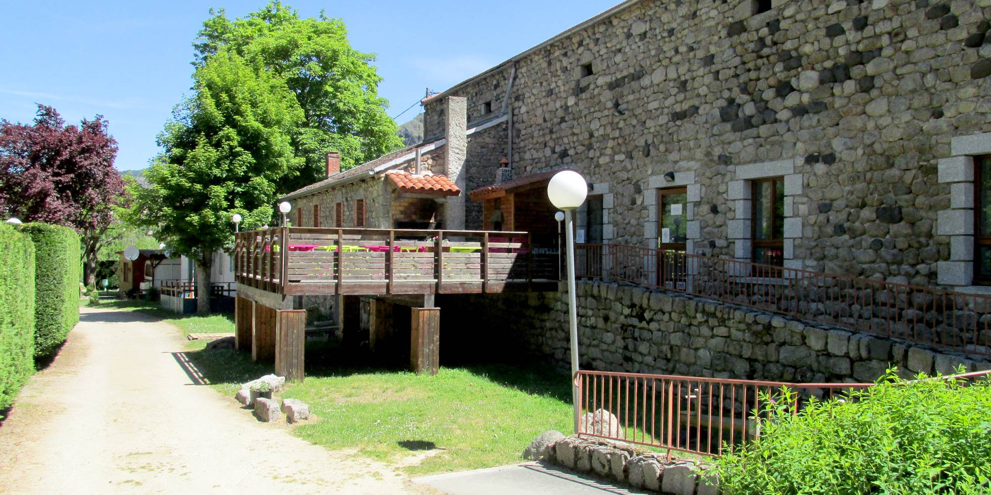Vue sur la terrasse côté camping et sur l'entée des sanitaires