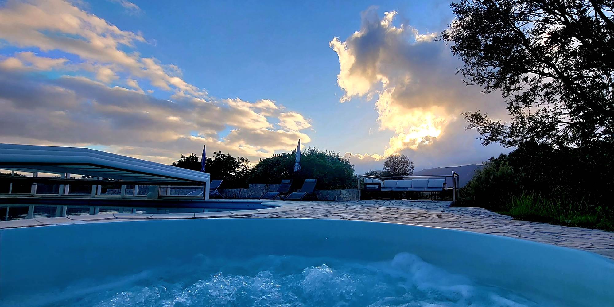 Moment de calme au bord de la piscine du domaine sous un ciel spectaculaire en Corse du Sud.