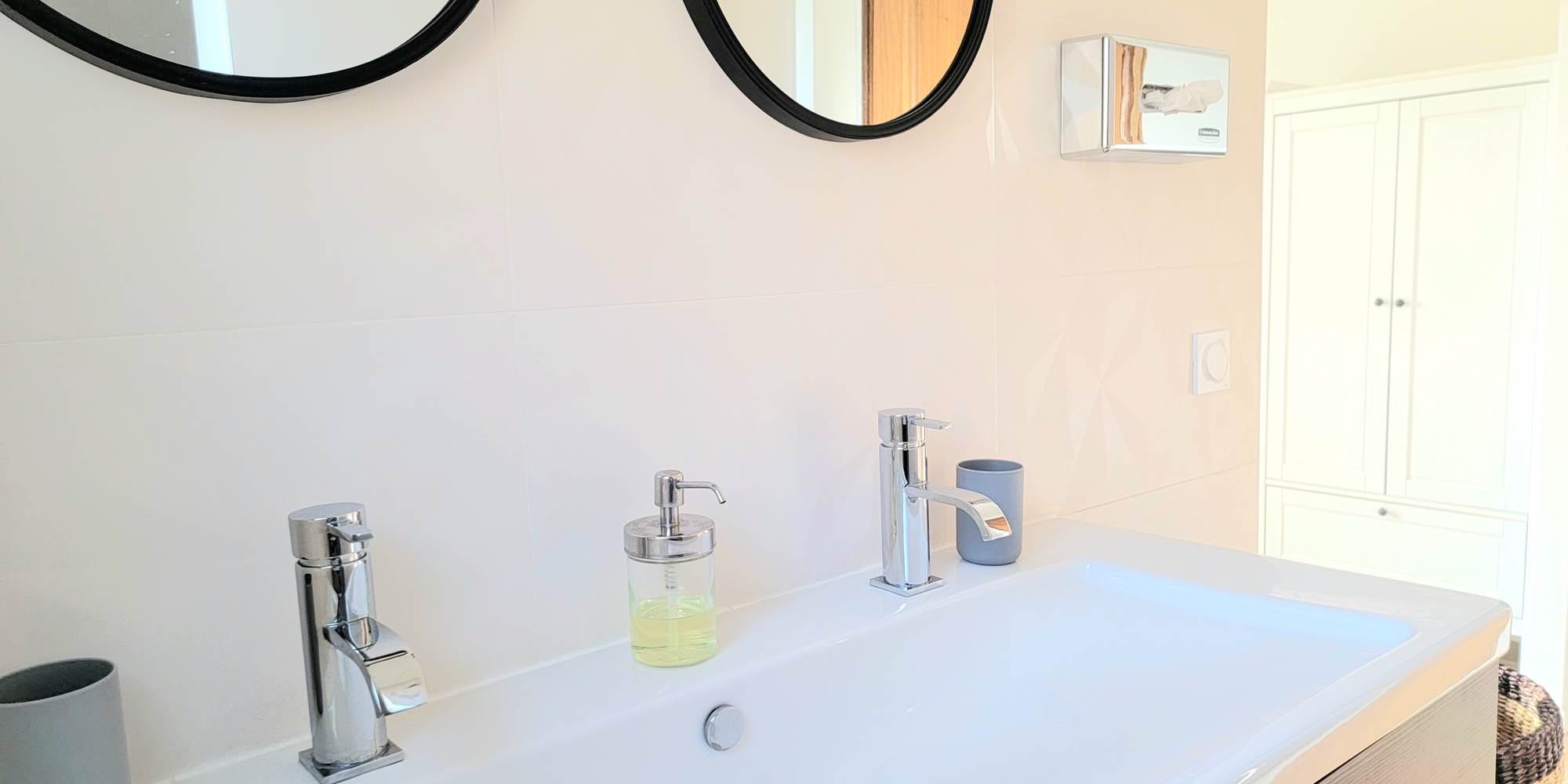 Salle de bain moderne et épurée avec double vasque, équipements de qualité au domaine.