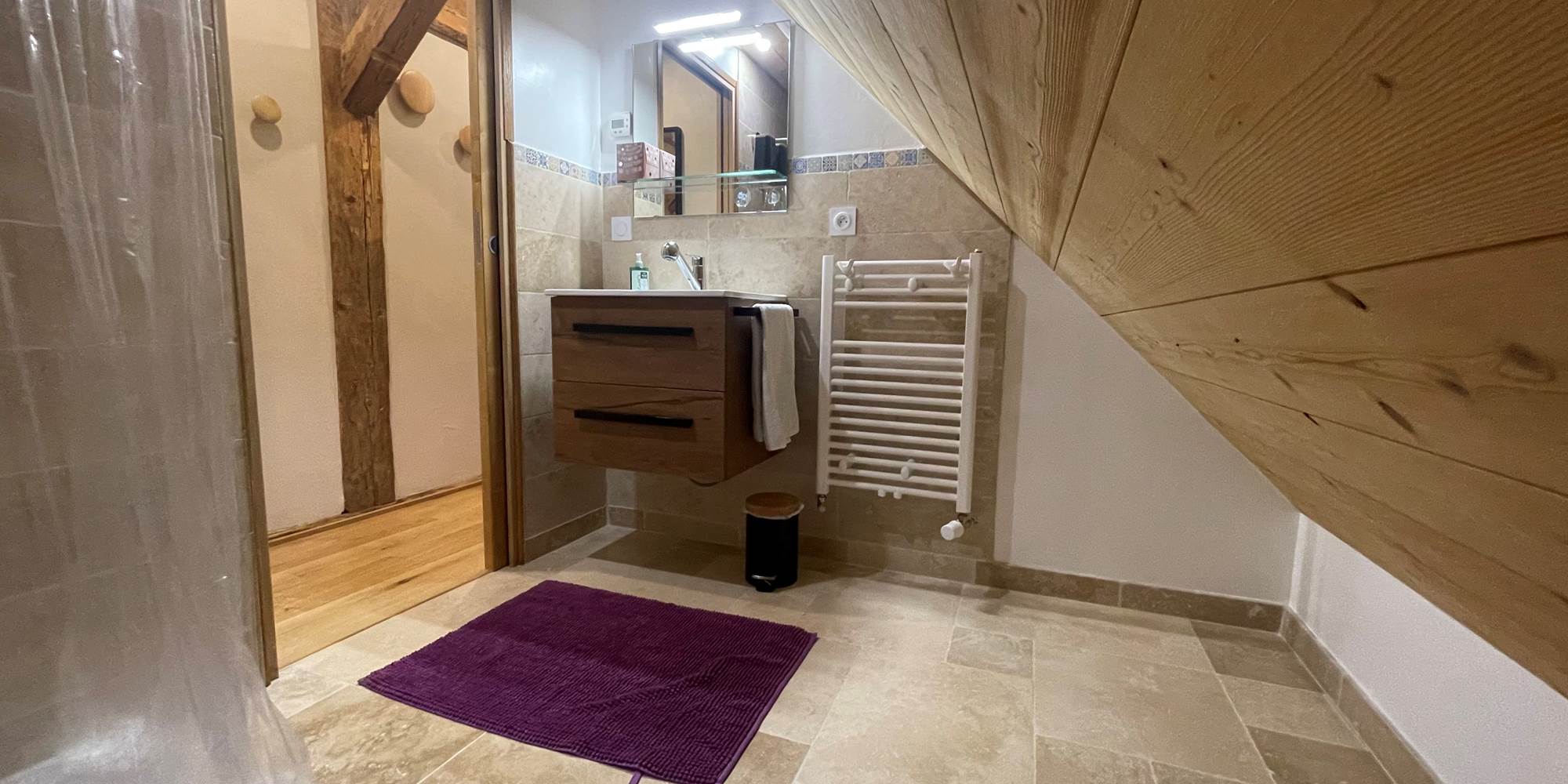 Salle de bain avec lavabo, douchette, sèche serviette et sèche cheveux.