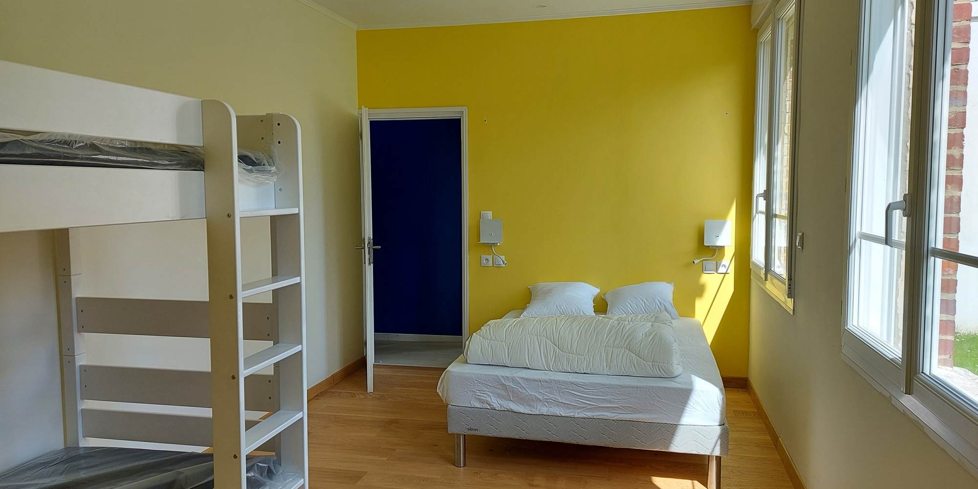 Chambre jaune lumineuse avec lit double 140x200 et lit superposé, idéale pour une famille avec enfants dans notre gîte du Pas-de-Calais.