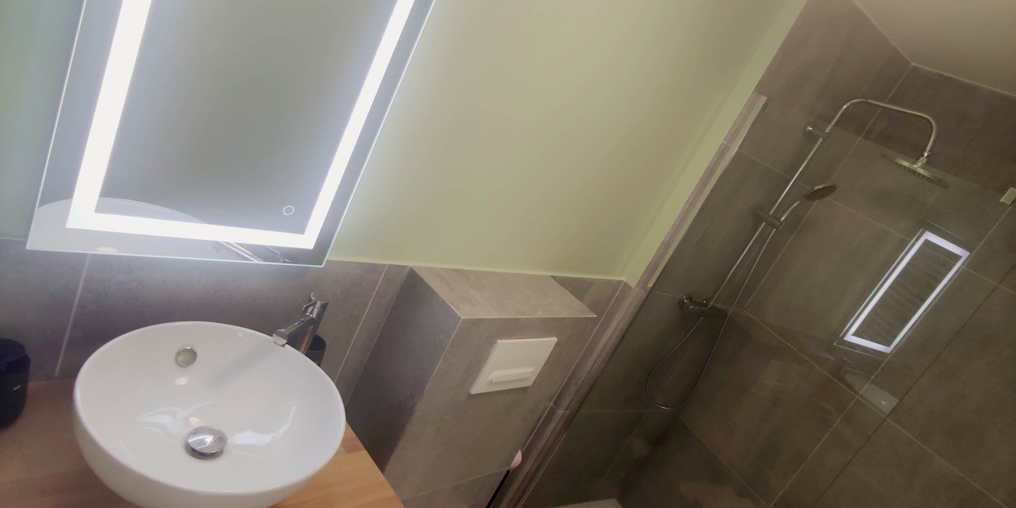 Salle d’eau contemporaine dans un esprit épuré Miroir rétroéclairé, vasque élégante et douche italienne : un espace bien pensé pour votre confort quotidien.