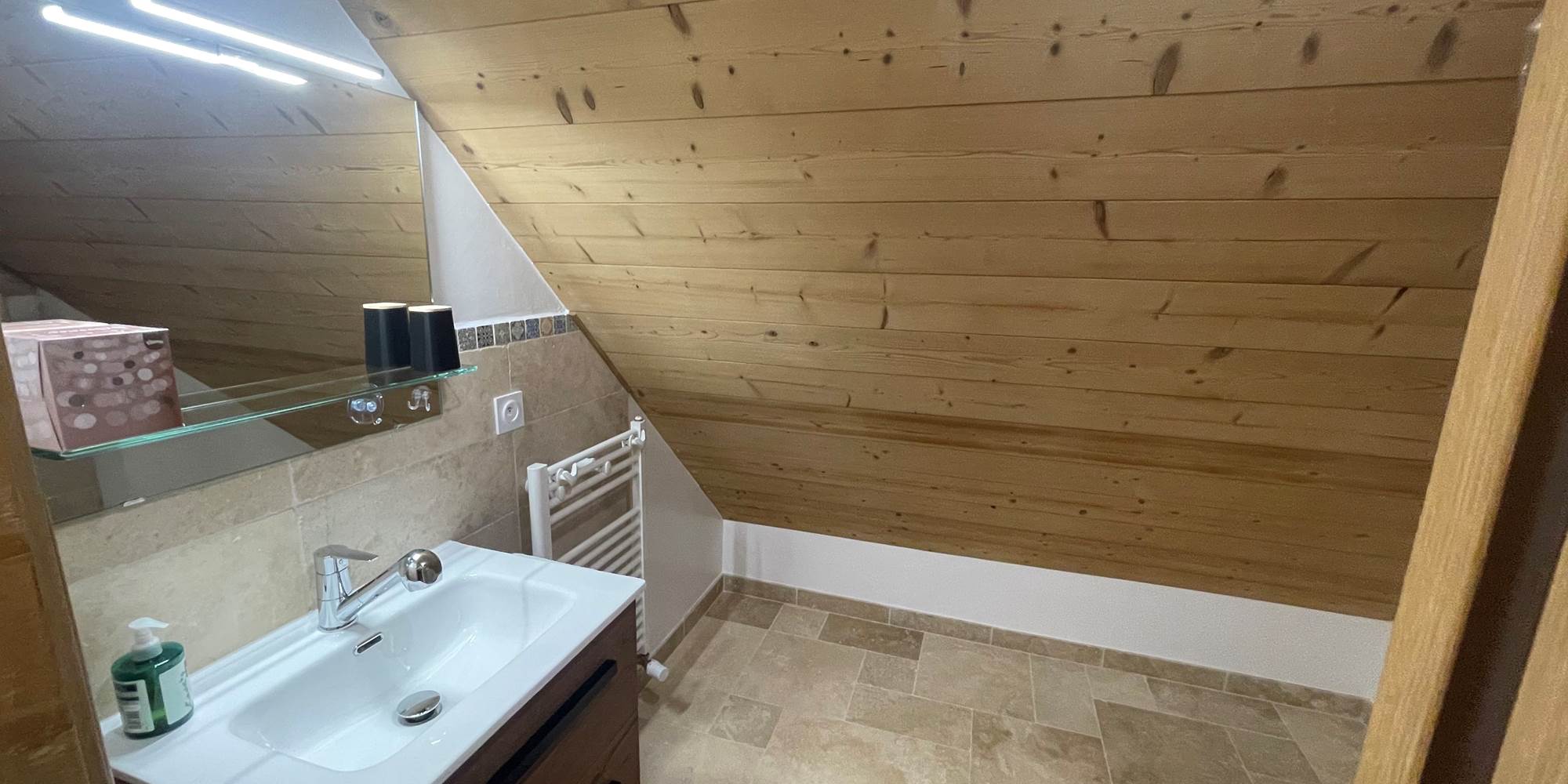 Salle de bain avec lavabo, douchette, sèche serviette et sèche cheveux.