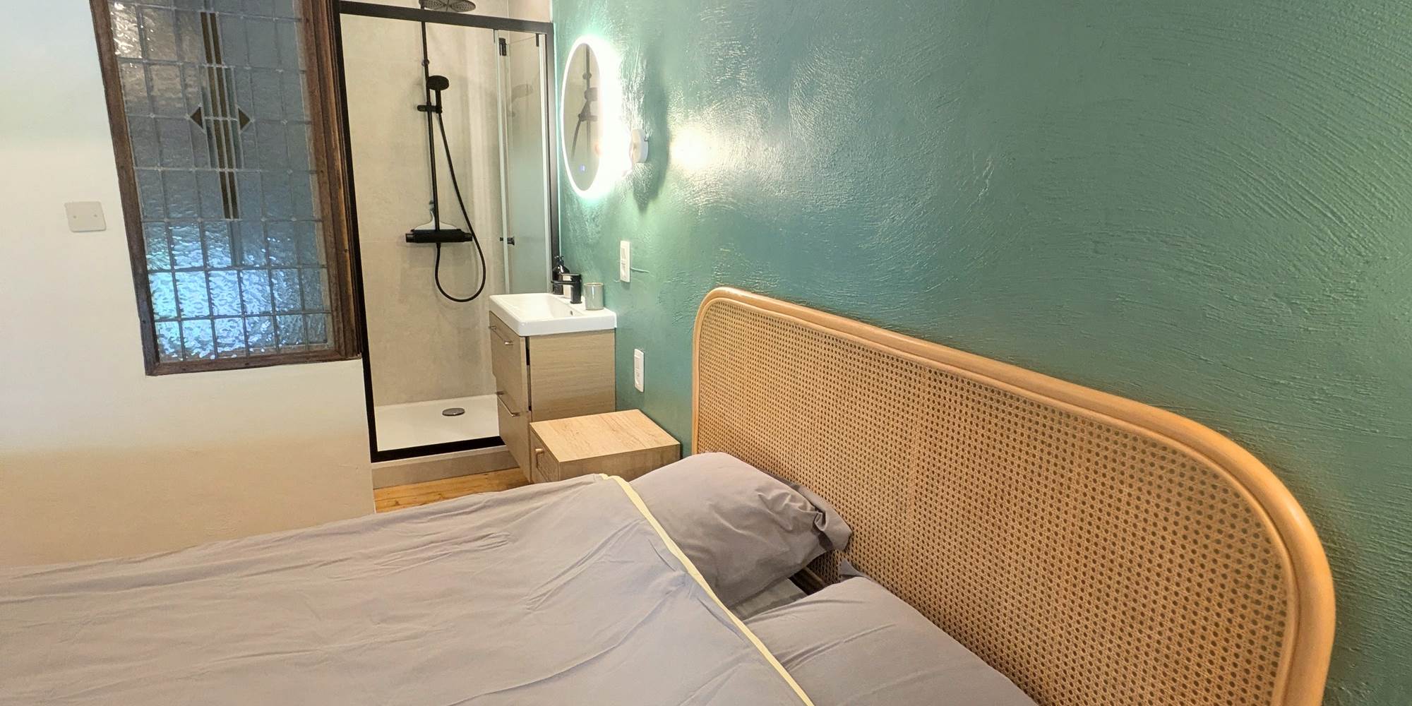 alt="Chambre lumineuse avec lit queen size et douche privée dans le grand gîte avec piscine intérieure"