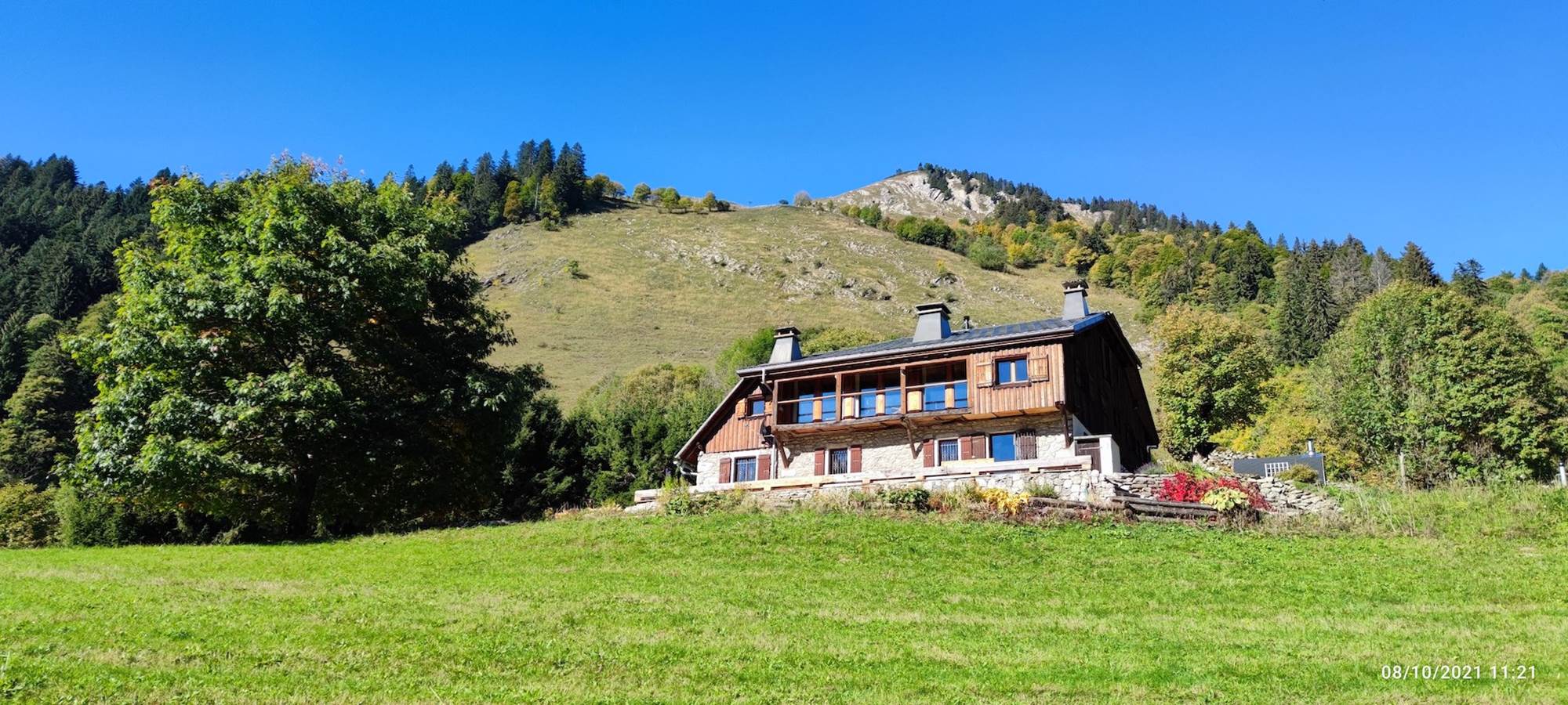 Façade en bois et pierre du chalet de Beauregard au cœur des alpages de Taninges face au massif du Roc d'Enfer