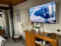Télévision dans le salon avec à gauche porte du cabinet de toilettes