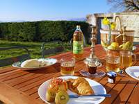 Petit-déjeuner gourmand en terrasse au gîte Le Manoir du Colombier, location de vacances avec vue sur le Grand Colombier et les montagnes du Bugey.