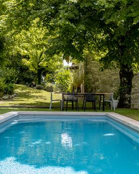 Table extérieure avec vue sur la piscine et le jardin arboré