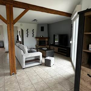 Espace salon équipé d’un canapé, d’un pouf et d’une TV.