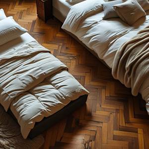lit d'appoint au sol d'une chambre cosy avec vieux parquet et tapis, grands lit à côté. une couette et un oreiller pour garnir le lit d'appoint