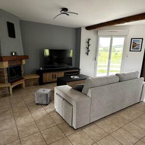 Espace salon équipé d’un canapé, d’un pouf et d’une TV.