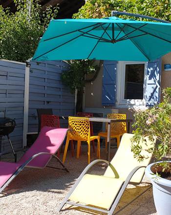 Terrasse devant le gîte, salon de jardin avec transats, parasol,  barbecue.