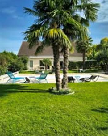 Un jardin arboré avec piscine propice à la détente après journée au Zoo de La Flèche ou aux lacs de la Monnerie