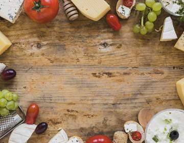 plateau-de-fromages-avec-tomates-raisins-et-mini-sandwichs-sur-un-bureau-en-bois-avec-espace-pour-ecrire-le-texte-min