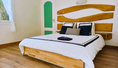 Chambre double lit queen size avec tête de lit bois sculpté, parquet chaud et literie blanche – chambre de charme Lauzerte Quercy Blanc