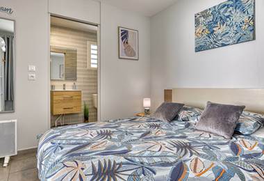 Chambre du Cocon d’Hell-Bourg avec lit queen size et salle d’eau attenante, alliant confort et élégance au cœur du cirque de Salazie, à La Réunion.