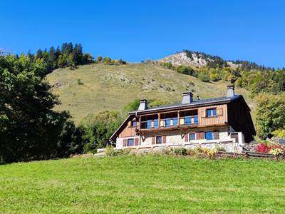 Façade en bois et pierre du chalet de Beauregard au cœur des alpages de Taninges face au massif du Roc d'Enfer