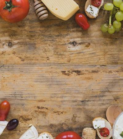 plateau-de-fromages-avec-tomates-raisins-et-mini-sandwichs-sur-un-bureau-en-bois-avec-espace-pour-ecrire-le-texte-min