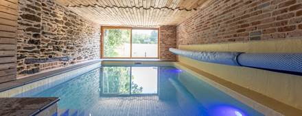 alt="Piscine intérieure chauffée du grand gîte familial en Ardenne belge pour séjours en groupe et vacances en famille"