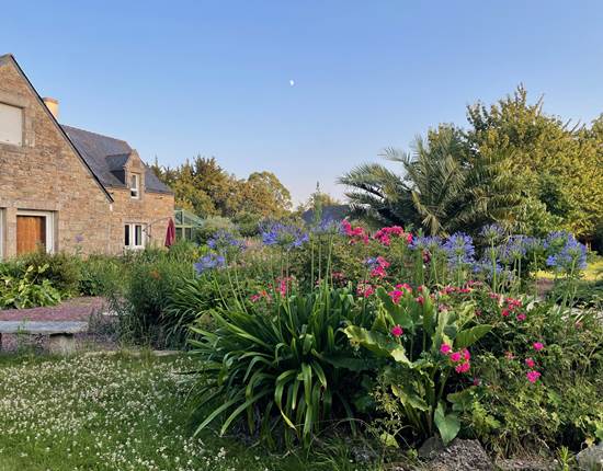 Maison entourée de massifs de fleurs (roses et agapenthes ici)