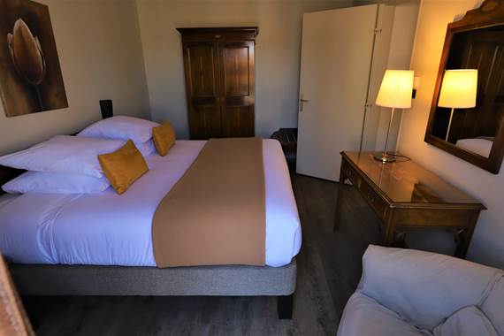Chambre avec grand lit, fauteuil et armoire