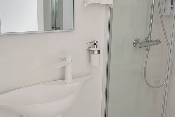 Salle d'eau fonctionnelle avec douche à l'italienne et petit lavabo.