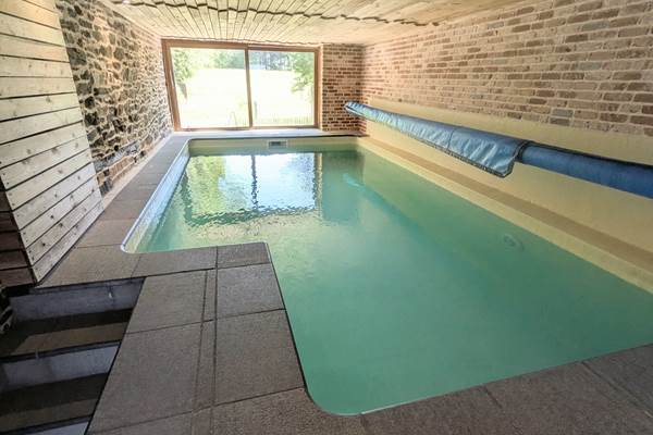 alt="Espace piscine couverte avec ambiance détente dans le gîte familial avec piscine en Belgique"