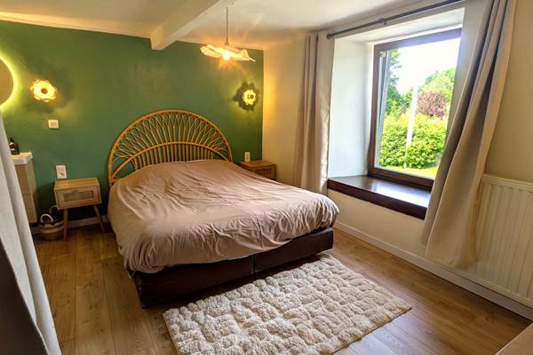 Bright queen size bedroom with large windows in countryside holiday home