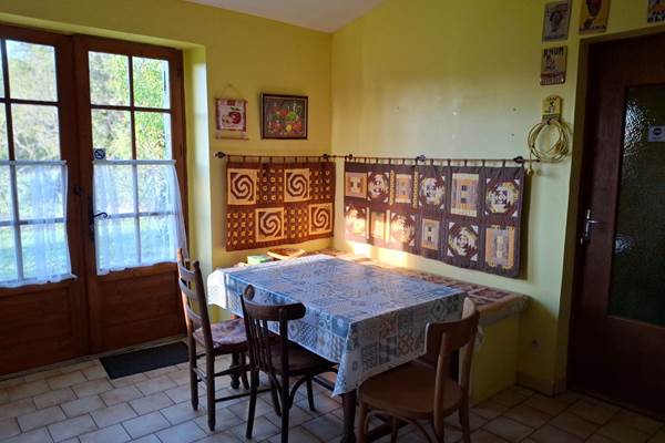 Espace repas lumineux dans la cuisine, avec accès jardin et vue nature, idéal pour repas d'appoint en famille ou entre enfants