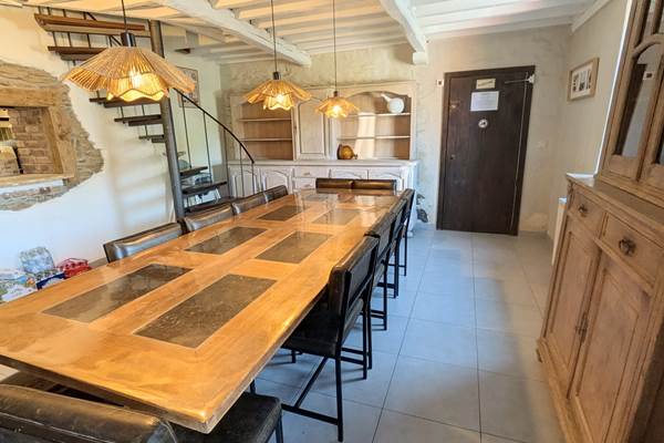 alt="Grande salle à manger du gîte familial avec table conviviale pour repas en groupe en Belgique"