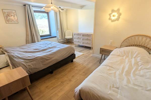 alt="Grande chambre familiale avec lit king size, lit simple et salle de douche privative dans le gîte en Belgique"
