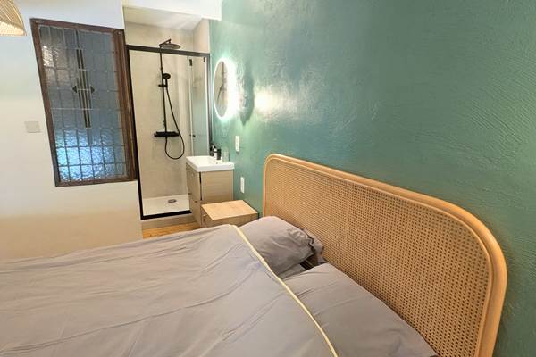 alt="Chambre lumineuse avec lit queen size et douche privée dans le grand gîte avec piscine intérieure"