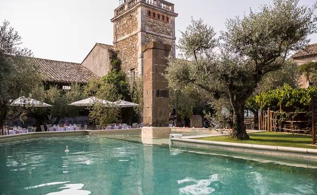 Grande piscine extérieure dans une cour fermée bordée d’oliviers centenaires