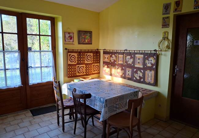 Espace repas lumineux dans la cuisine, avec accès jardin et vue nature, idéal pour repas d'appoint en famille ou entre enfants