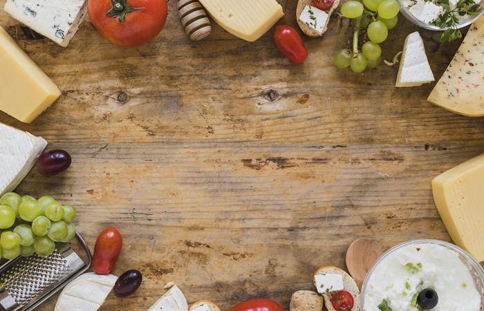 plateau-de-fromages-avec-tomates-raisins-et-mini-sandwichs-sur-un-bureau-en-bois-avec-espace-pour-ecrire-le-texte-min